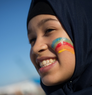 Closeup of a young woman's face with rainbow facepaint