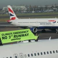 Activists with "no 3rd runway banner" stand on top of plane