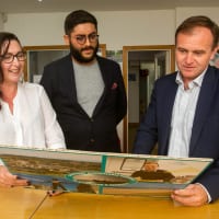 Accompanied by a Greenpeace campaigner, George Eustice looks at an oversized display board with sustainable fishing messages.