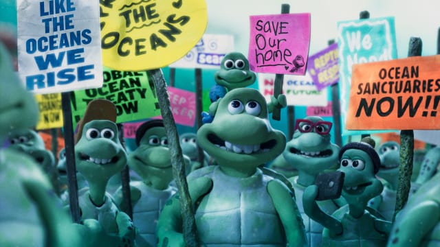 Still from an animation showing cartoon turtles smiling at a protest, holding placards calling for ocean protection