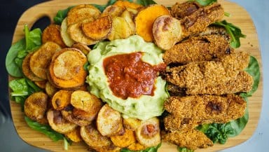 Overhead photo of a sharing platter with spiced fried potates, spinach, guacamole and salsa.
