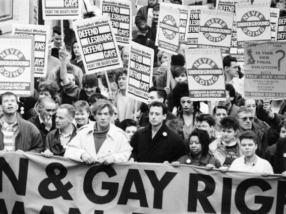Black and white photo of protestors holding banners and placards advocating for LGBT rights