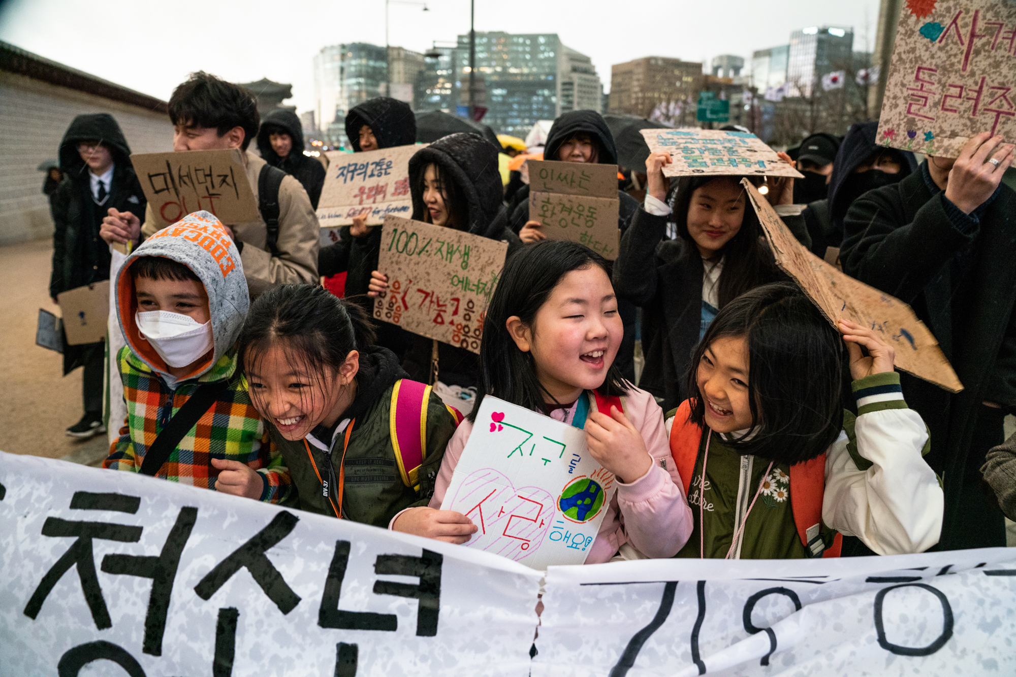 Korean students smiling and holding banners and placards as part of a demonstration.