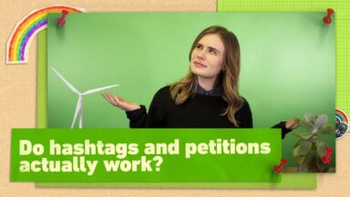 Video presenter Lex Croucher (long hair, black sweater) looks up with a puzzled expression and open-palm gesture against a green background. Text reads 'Do hashtags and petitions actually work?'