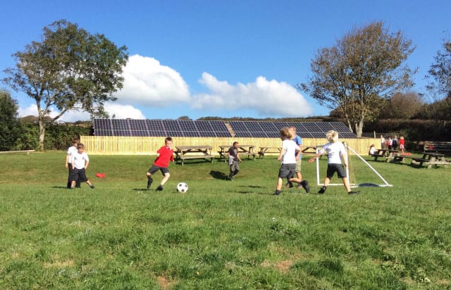 Pupils at Georgeham Primary in Devon play football in front of the school's new solar panels