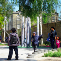 Children playing on Van Gogh Walk in London, with trees, play equipment and a basketball hoop in the background.