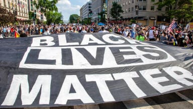 Giant black lives matter banner with a crowd of protestors in the background