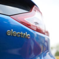 Closeup of the back of a modern car with the word 'electric' embossed on the paintwork.