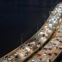 Heavy traffic on a multi-lane elevated motorway at night.