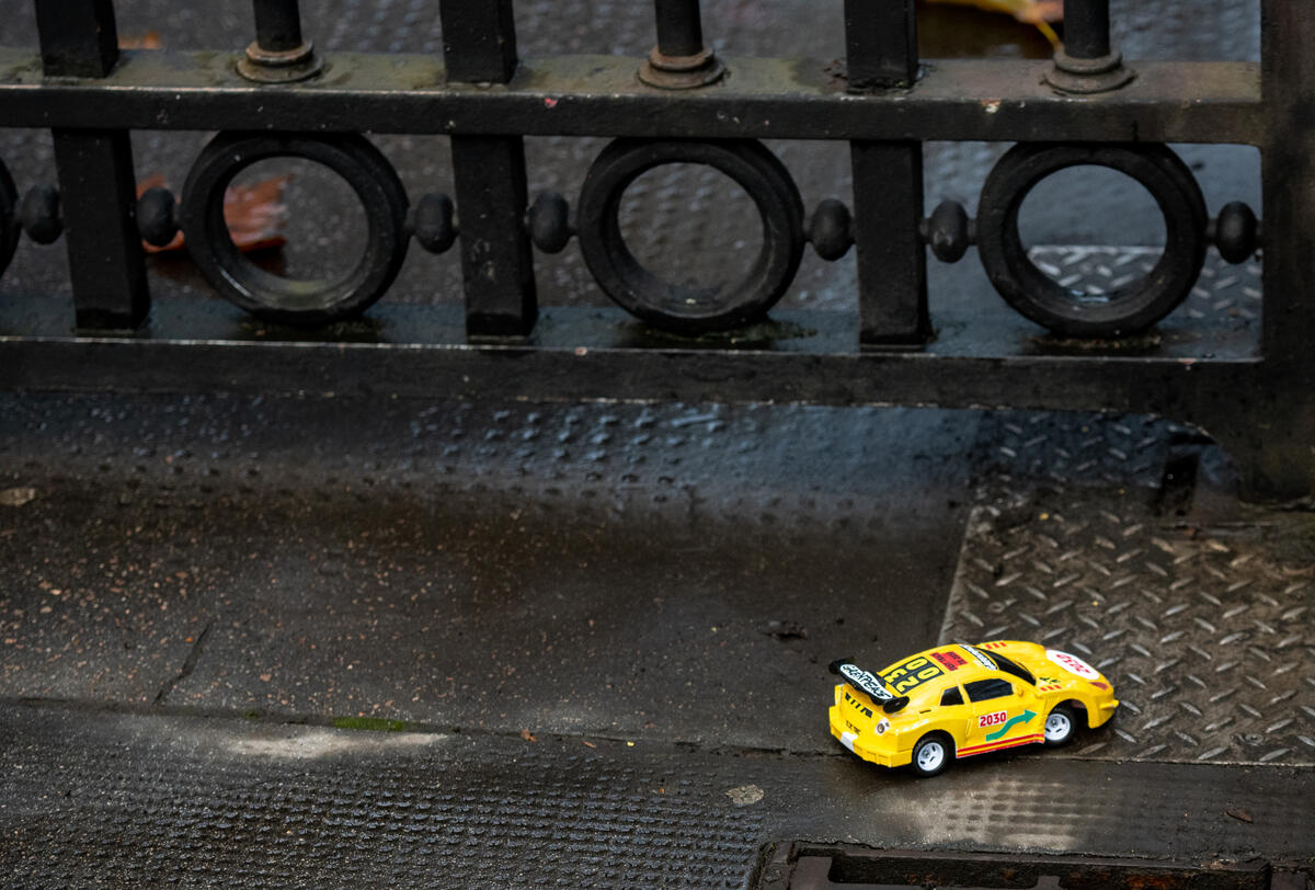 The tiny remote controlled car passes under the Downing Street gates.