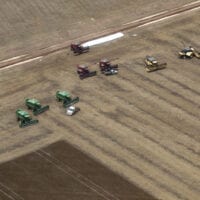 Aerial view of farm machinery working in a vast brown field