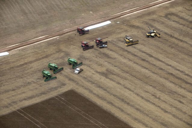 Aerial view of farm machinery working in a vast brown field
