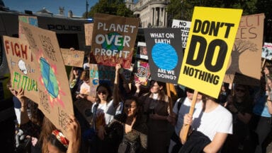 Protestors carry placards saying 'Don't do nothing' and 'Planet over profit'