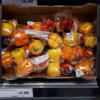 Plastic-wrapped red and yellow peppers on a supermarket display
