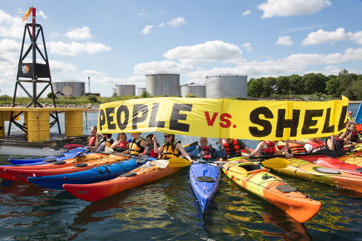 Protestors in kayaks hold a banner saying people vs Shell
