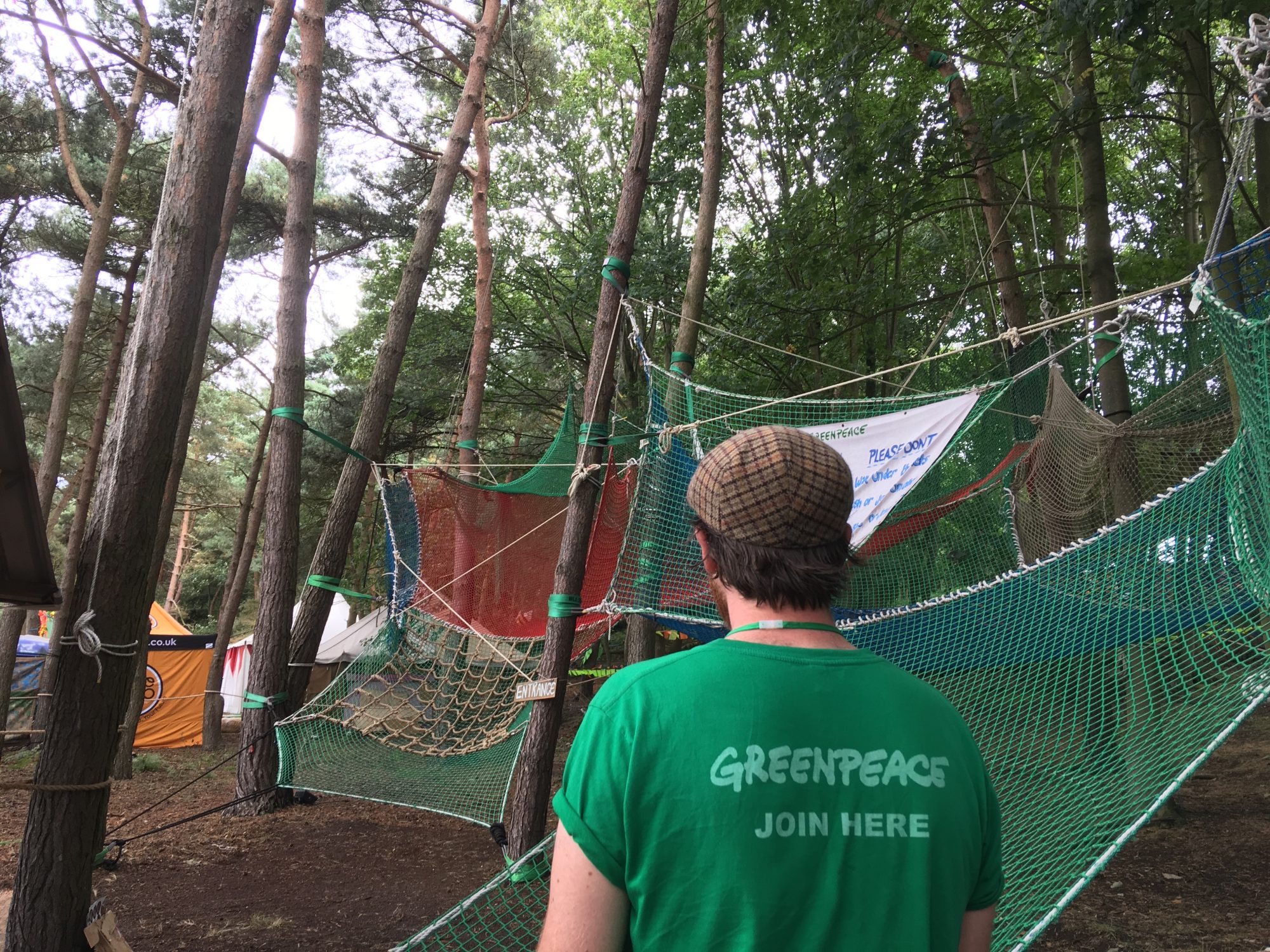 A Greenpeace volunteer stands in front of an obstacle course made of nets attached to trees