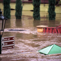 The top of a lamp post and street sign are just visible above the water level in a flooded city street