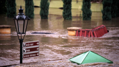 The top of a lamp post and street sign are just visible above the water level in a flooded city street