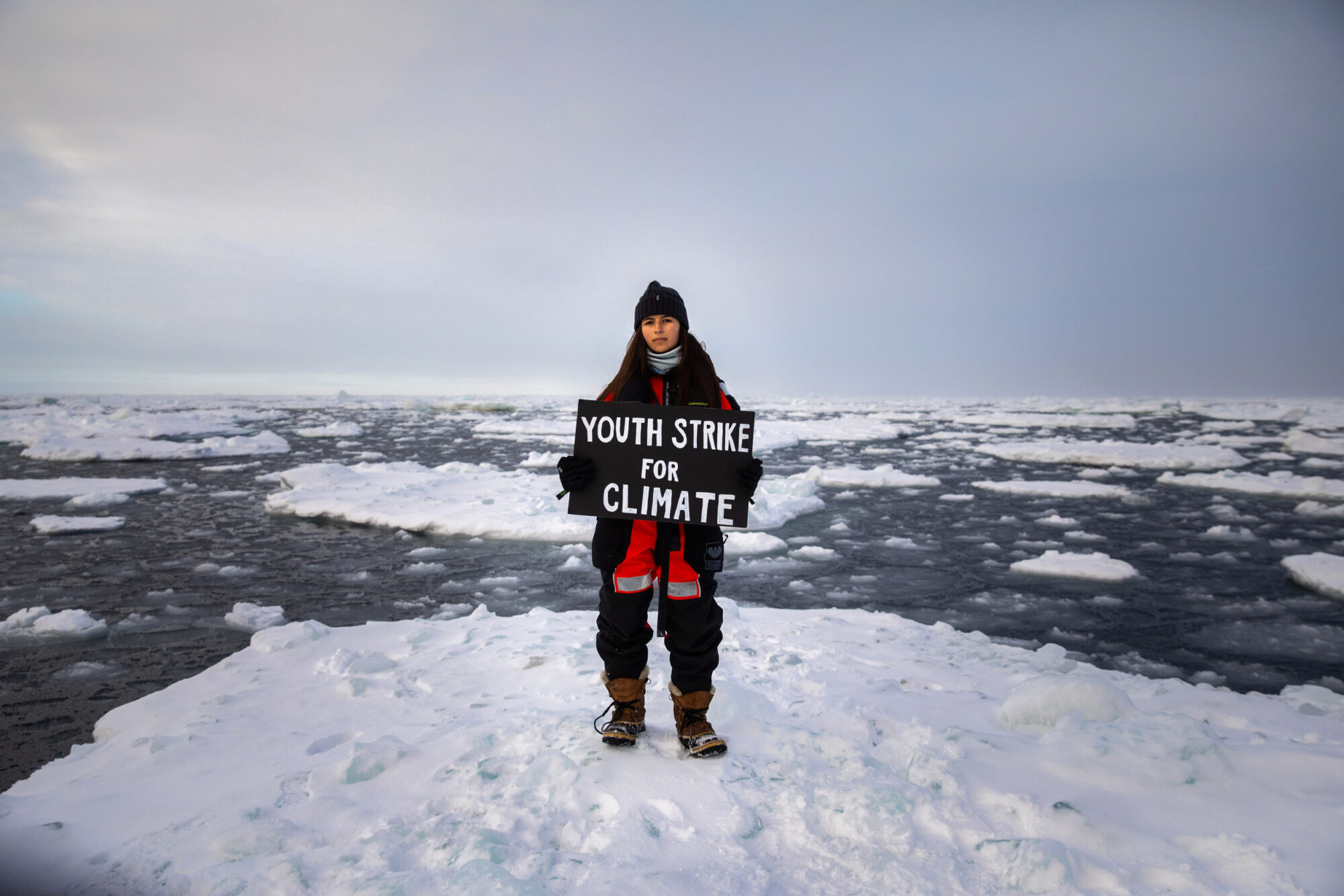 Mya-Rose Craig standing on ice holding a sign reading 'Youth strike for climate'