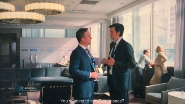 Screenshot from the TV show Succession. Main characters Tom and Greg stand face-to-face in a plush corporate lounge. The subtitle reads "You're going to sue Greenpeace?"