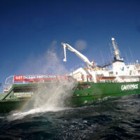 A boulder throws up a plume of rainbow spray as it's released from the Greenpeace ship Esperanza into the sea.