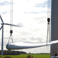 A wind turbine blade being lifted on a giant crane