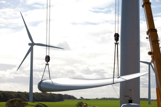 A wind turbine blade being lifted on a giant crane