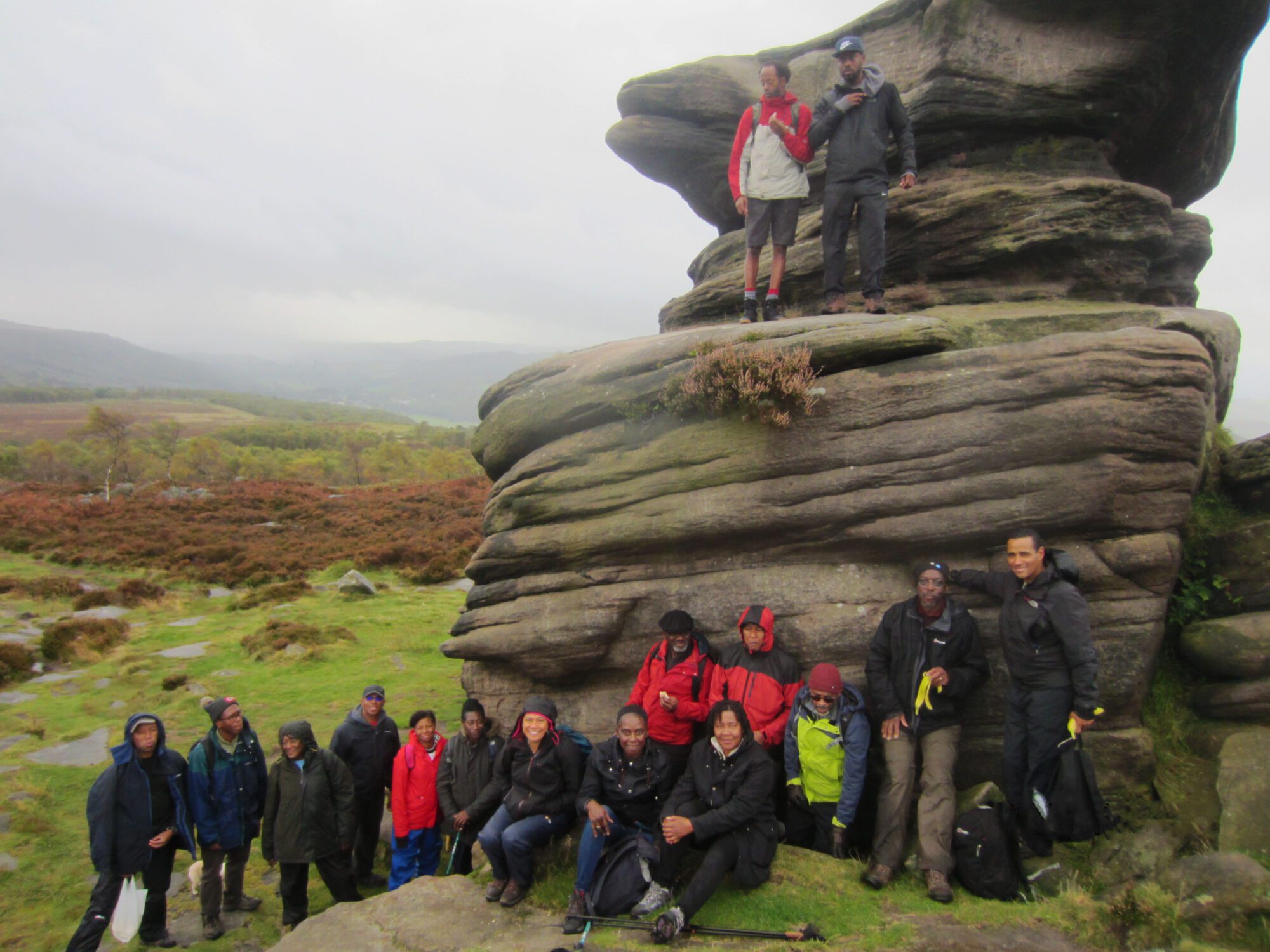 100 Black men walking group standing by a large rock in the UK countryside