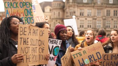 Group of women holding signs at a climate protest. The ones we can easily read say: ‘Be part of the solution, not part of the pollution’ and ‘It’s a beautiful world, let’s keep it that way!’