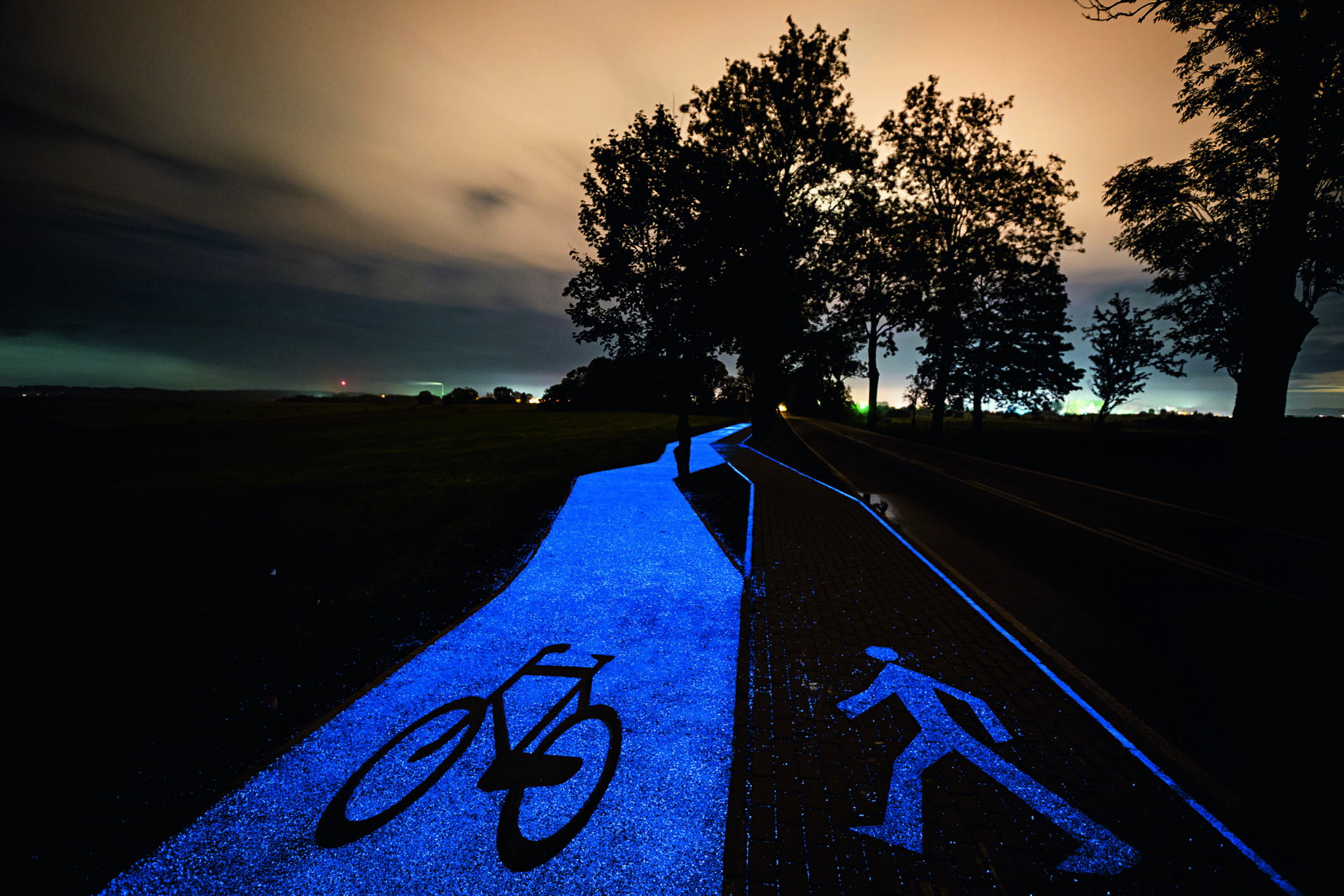 A cycle path and pedestrian path glow blue as the sun sets.