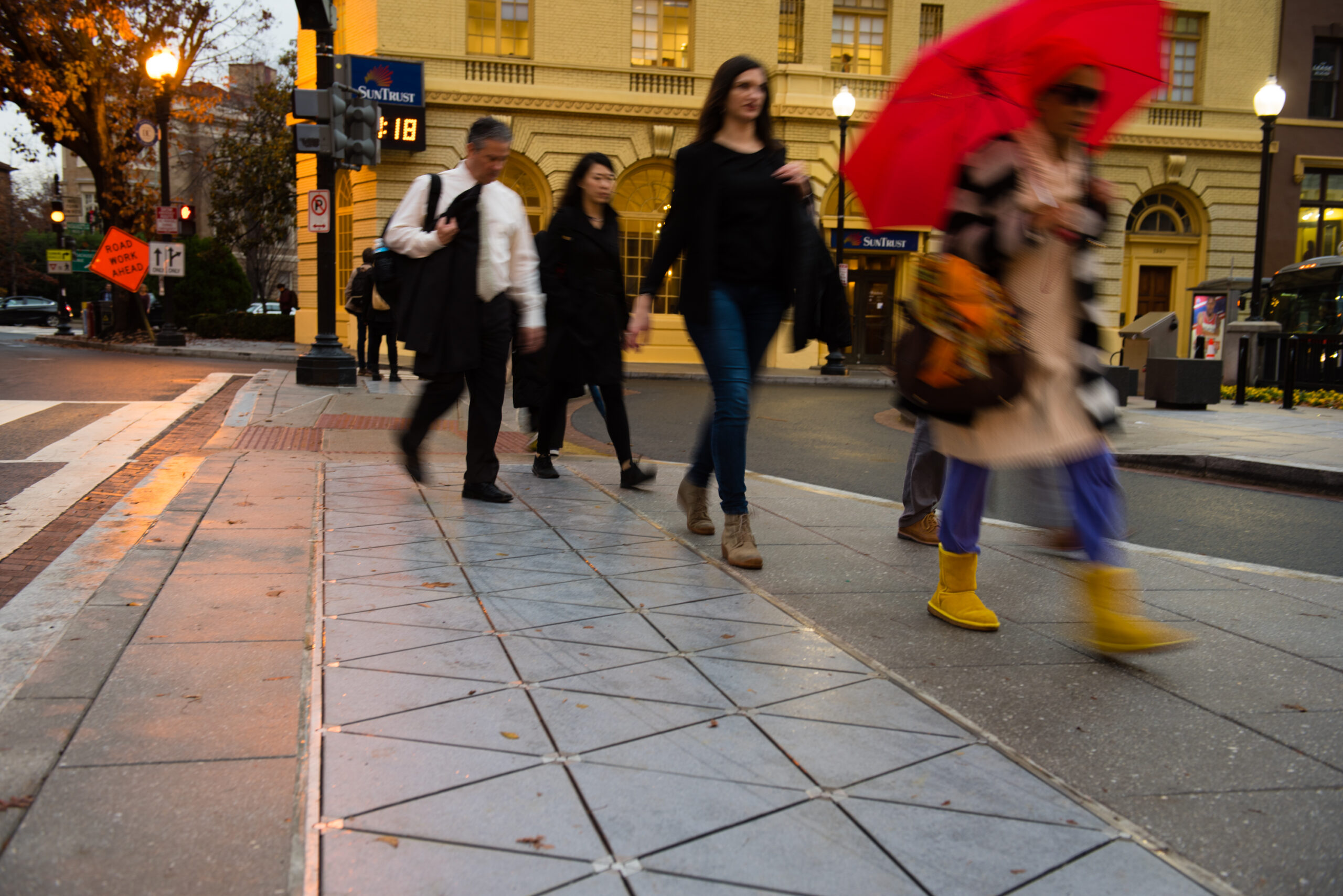People walk on a pavement made from triangular tiles.