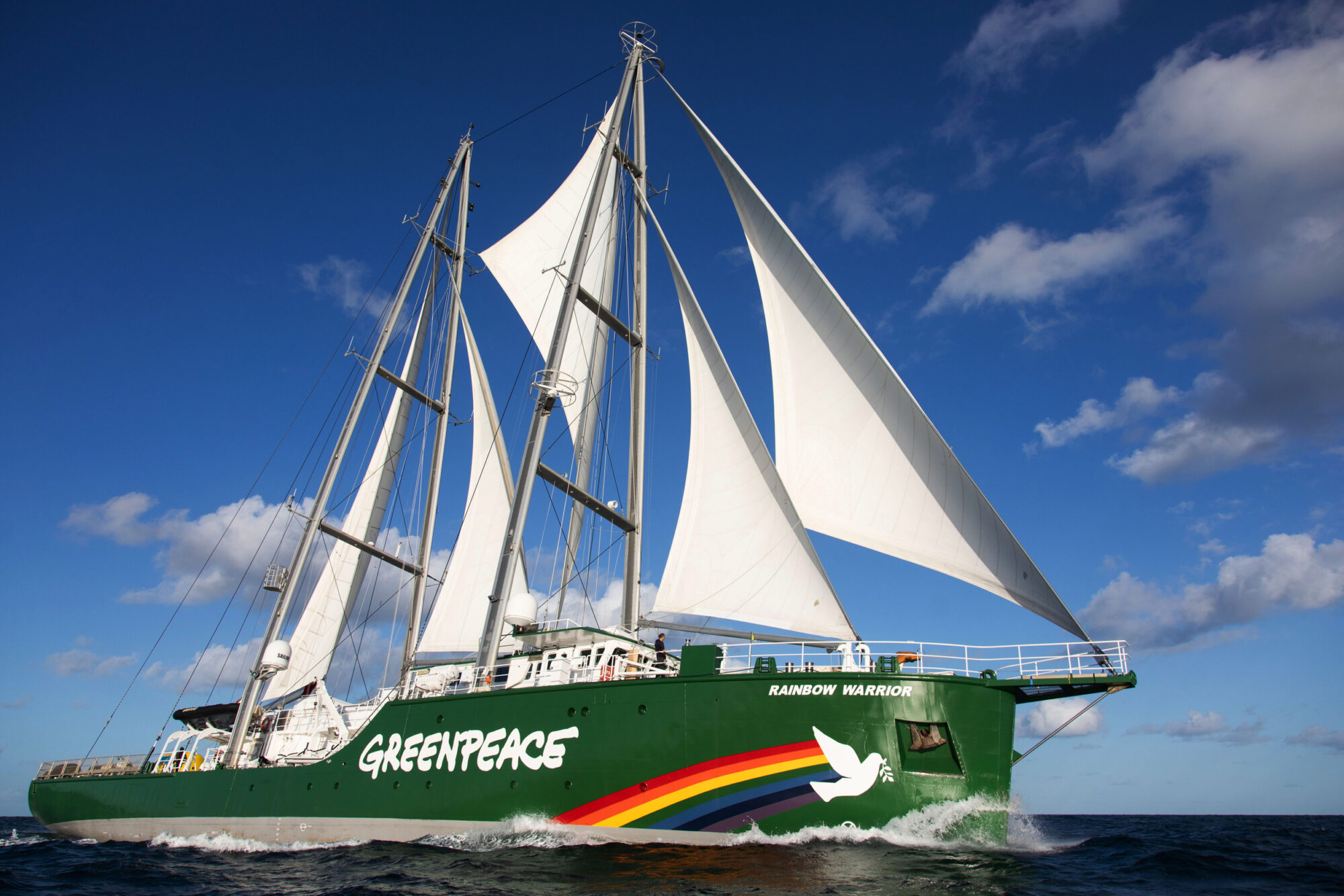 The Greenpeace ship Rainbow Warrior with beautiful white sails and a rainbow design on its bow