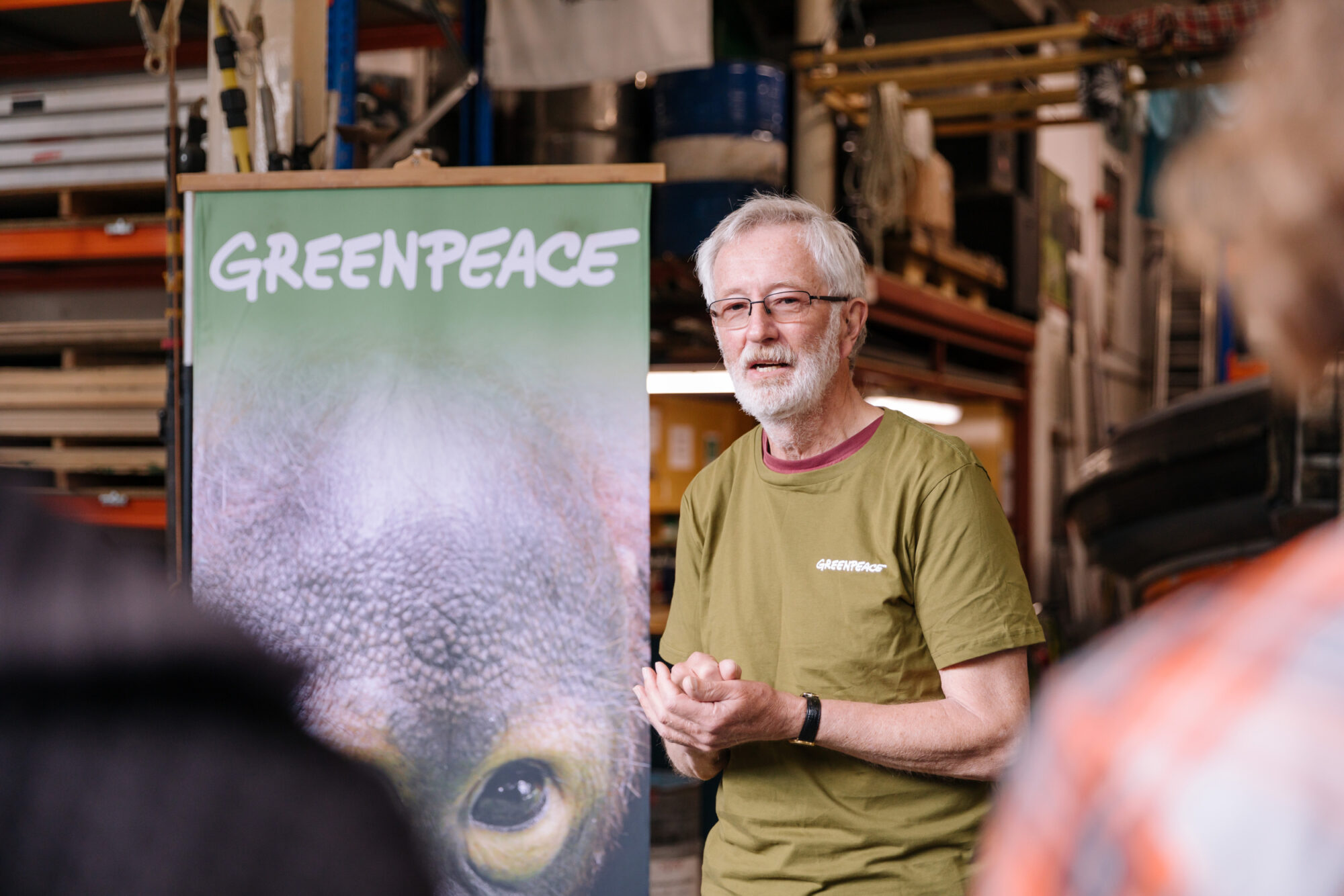 A speaker delivers a talk standing next to a Greenpeace banner