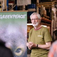 A speaker delivers a talk standing next to a Greenpeace banner