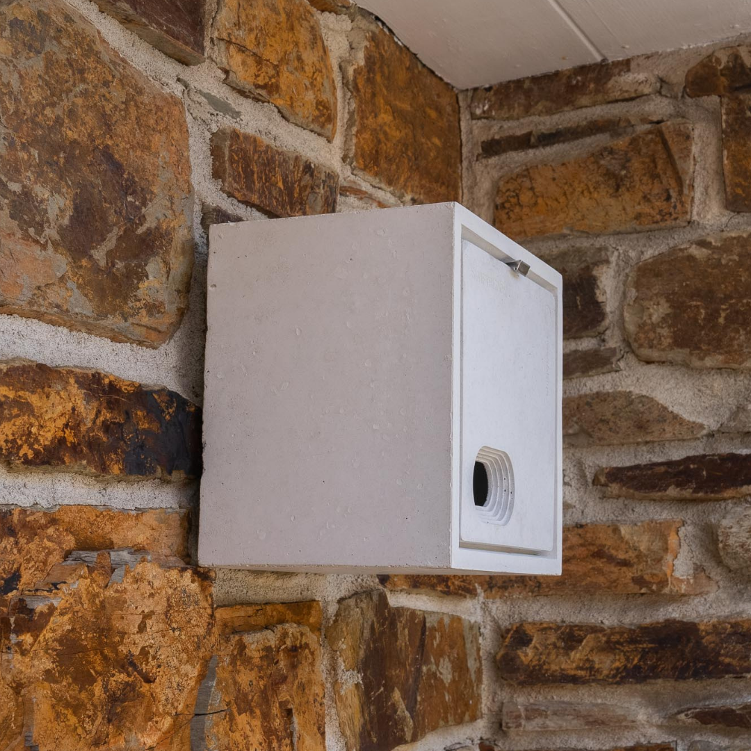 A white bird box for swifts mounted on a brick wall