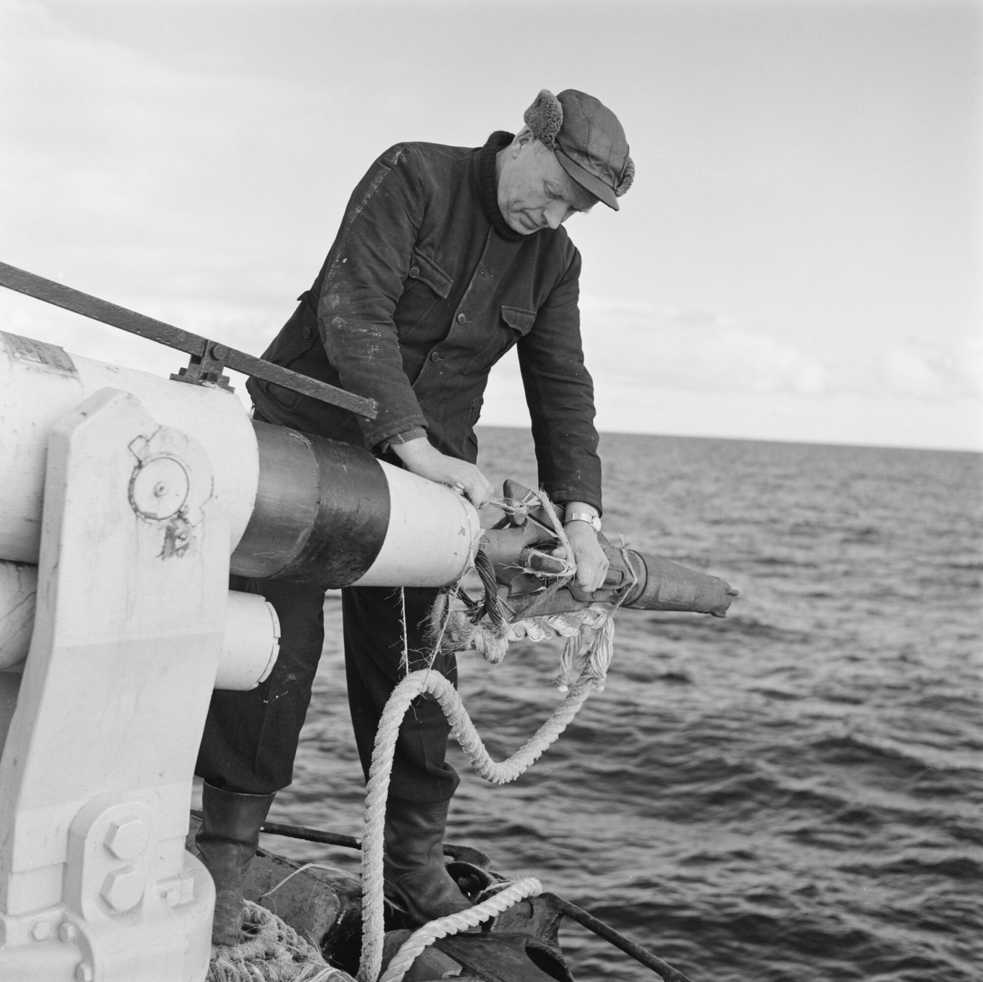 A man loading a harpoon with the sea behind him