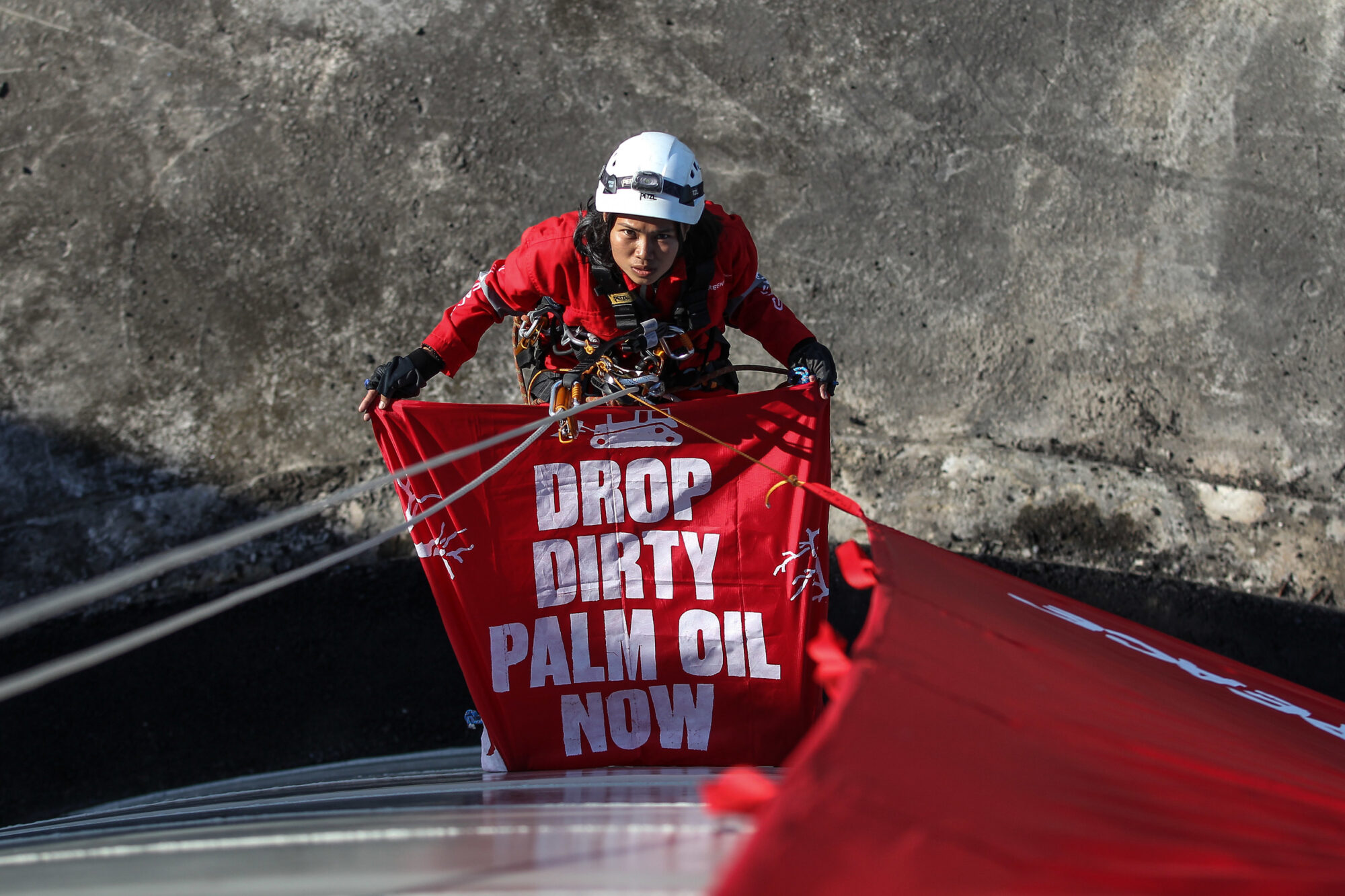 Activist holding banner saying "Drop dirty palm oil now"