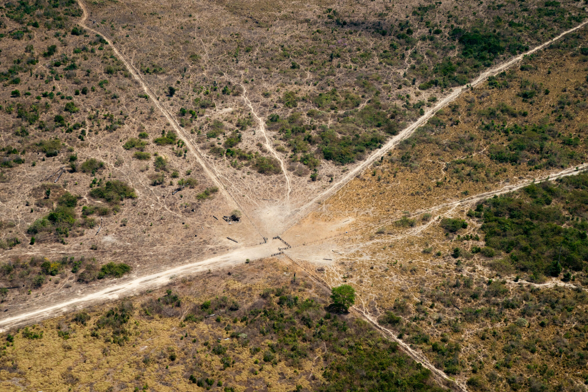 Aerial view of roads and pathways running through a dry, scrubby landscape. Coming from all directions, they converge in the middle of the frame.