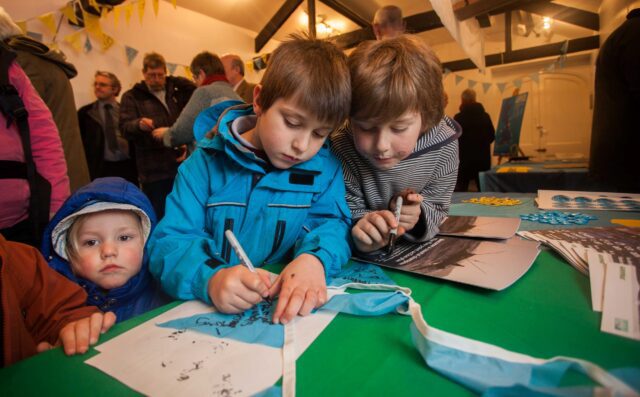 Two boys writing on bunting at an event