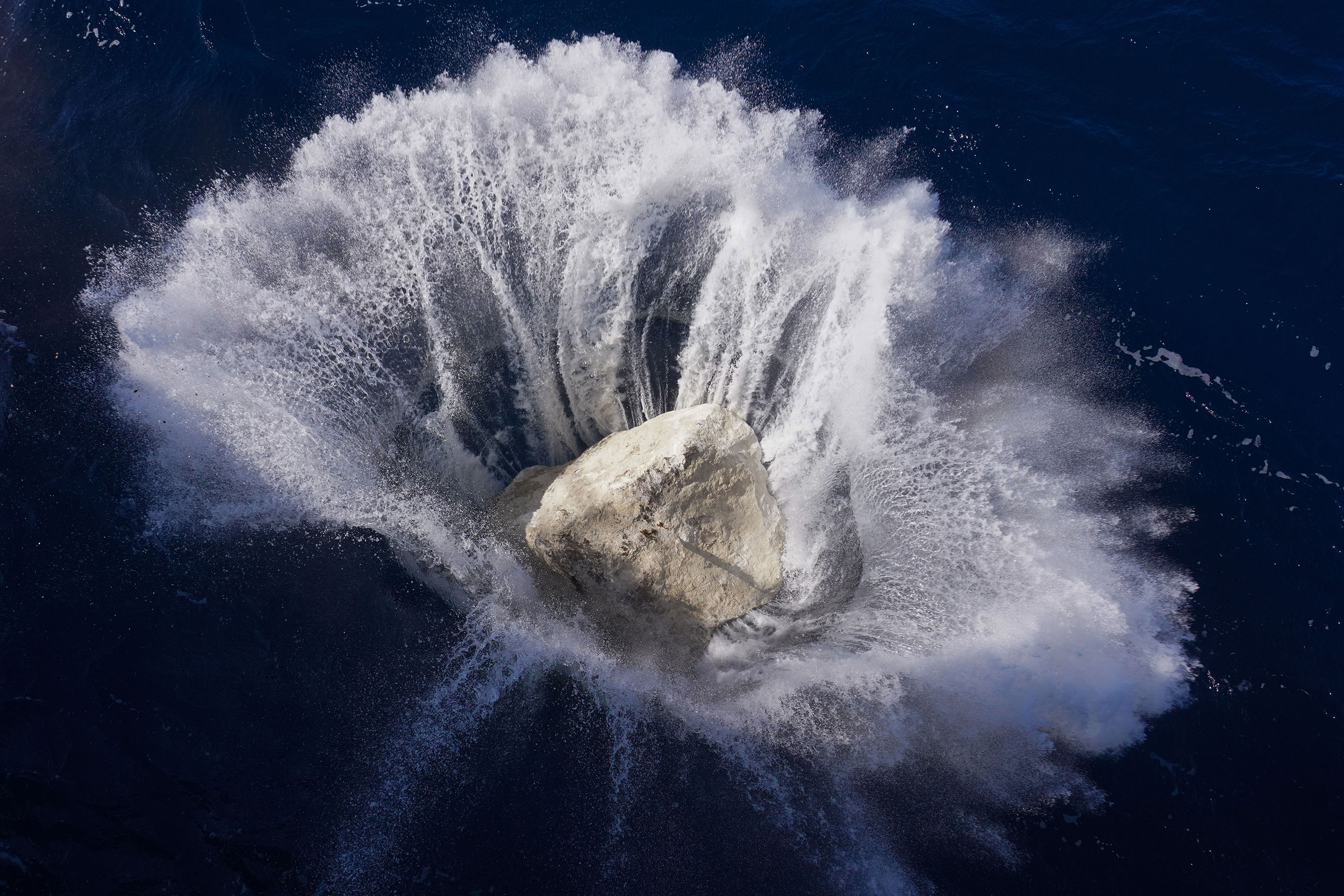 A boulder splashes into the water