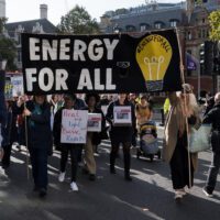 Fuel poverty protesters walk along a street with banners reading "Energy for all" and "Heat and light are basic rights"