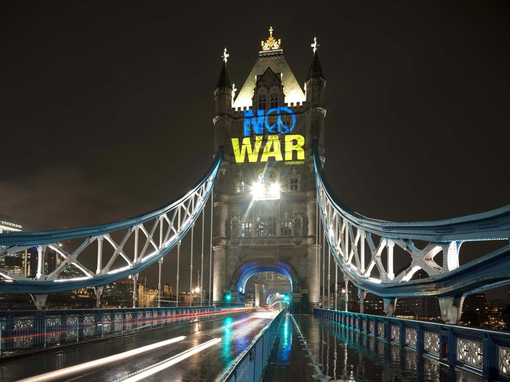 “No war” projected in blue and yellow (the colours of the Ukrainian flag) onto Tower bridge at night. The O in “no” has been changed to a peace sign.