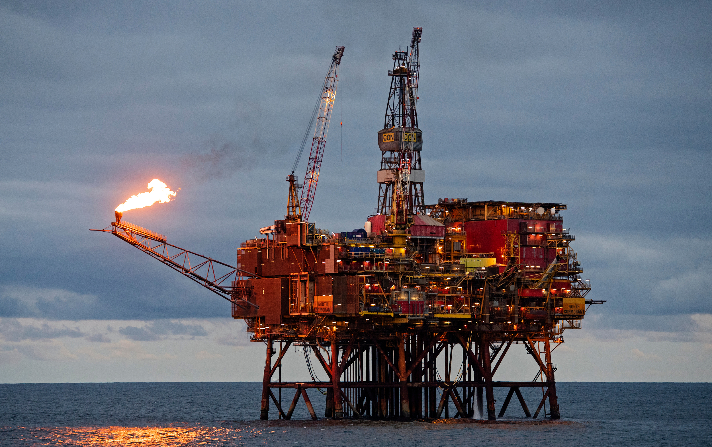 A flame bursts from the arm of a large oil rig in the sea