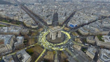Traffic spreading bright yellow paint from the Arc de Triomphe onto surrounding roads, creating the shape of a sun when seen from above.