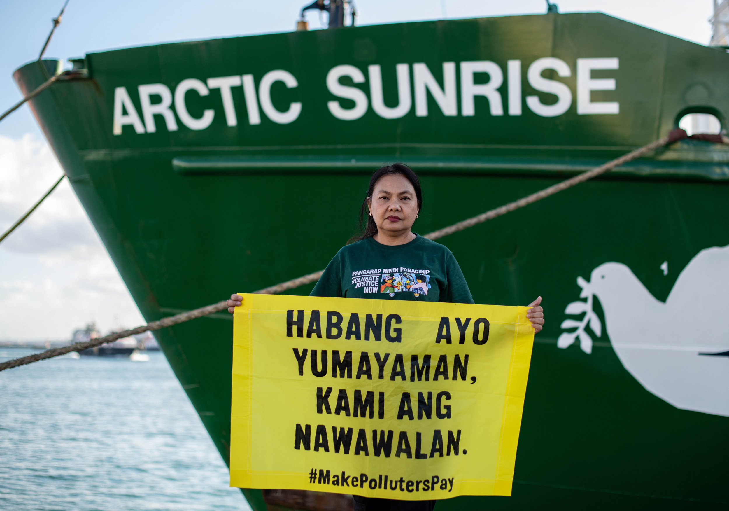 Virginia holds a yellow banner in front of the Arctic Sunrise.