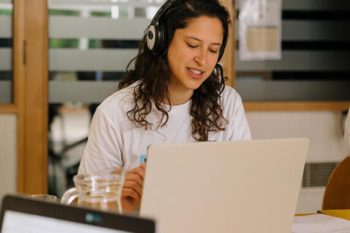 A woman with a headset and laptop takes part in a call