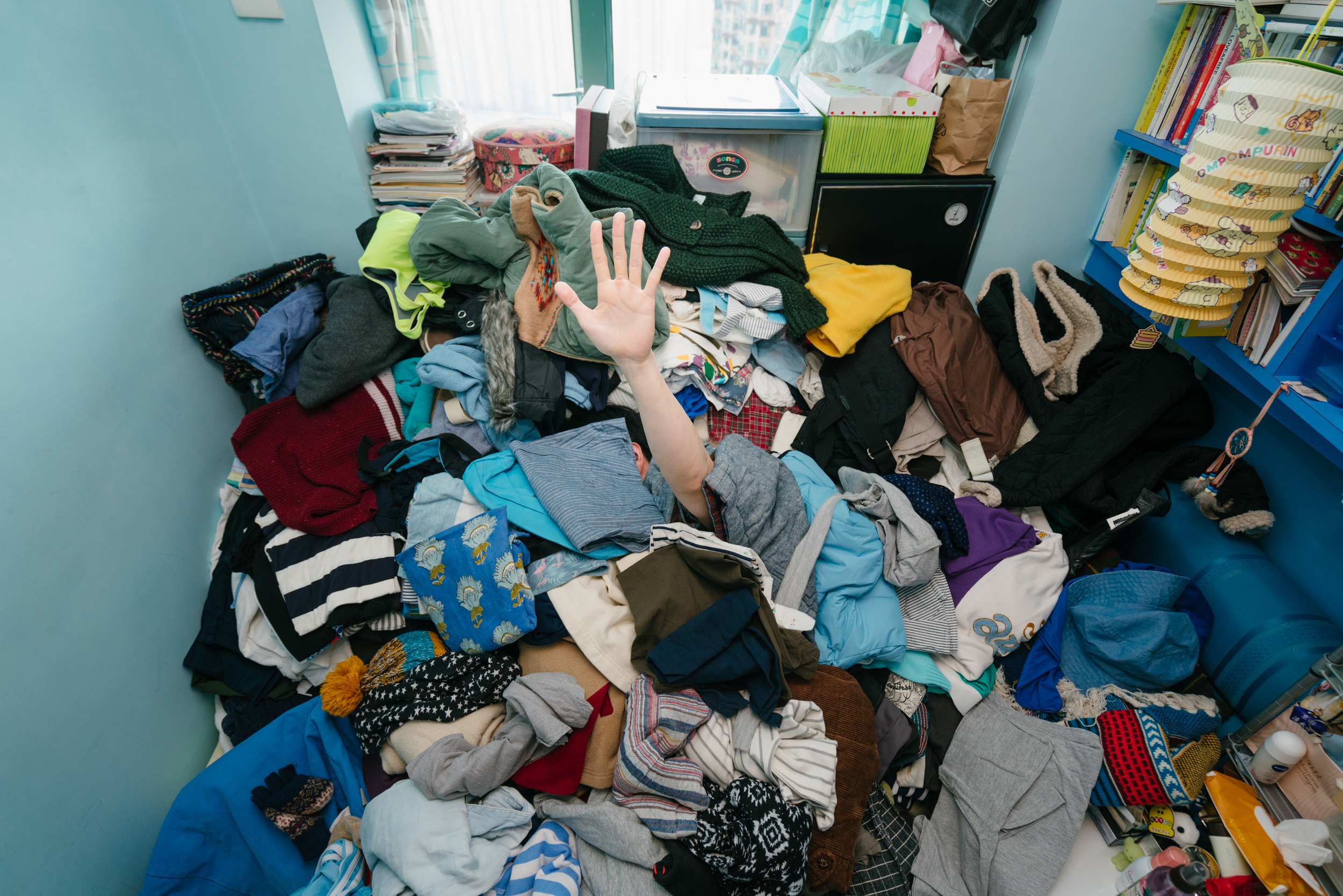 A solitary arm erupts from a huge pile of clothes.
