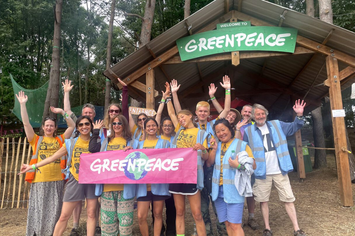 Greenpeace volunteers pose for a group photo in front of a beautiful forest.