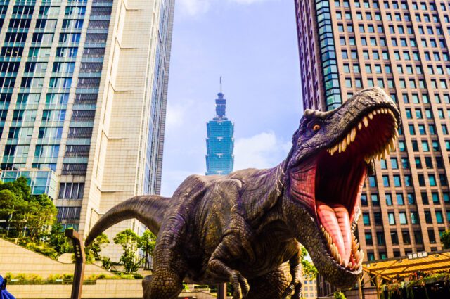 Digital illustration of a t-rex roaring with skyscrapers in the background.