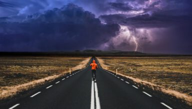 Photo montage of a lone runner on a straight road, with a dark, stormy sky ahead, representing eco-anxiety.